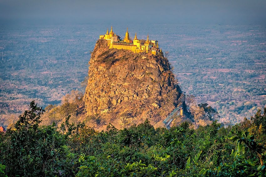 A golden Buddhist monastery perched on a hilltop