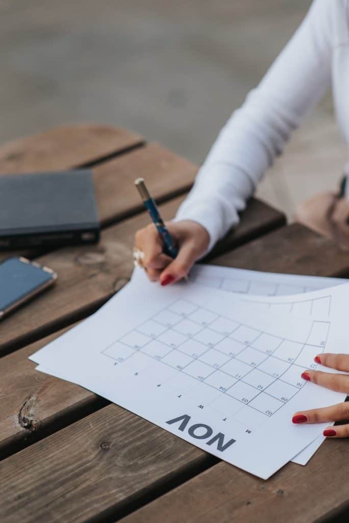 Crop woman making schedule in calendar