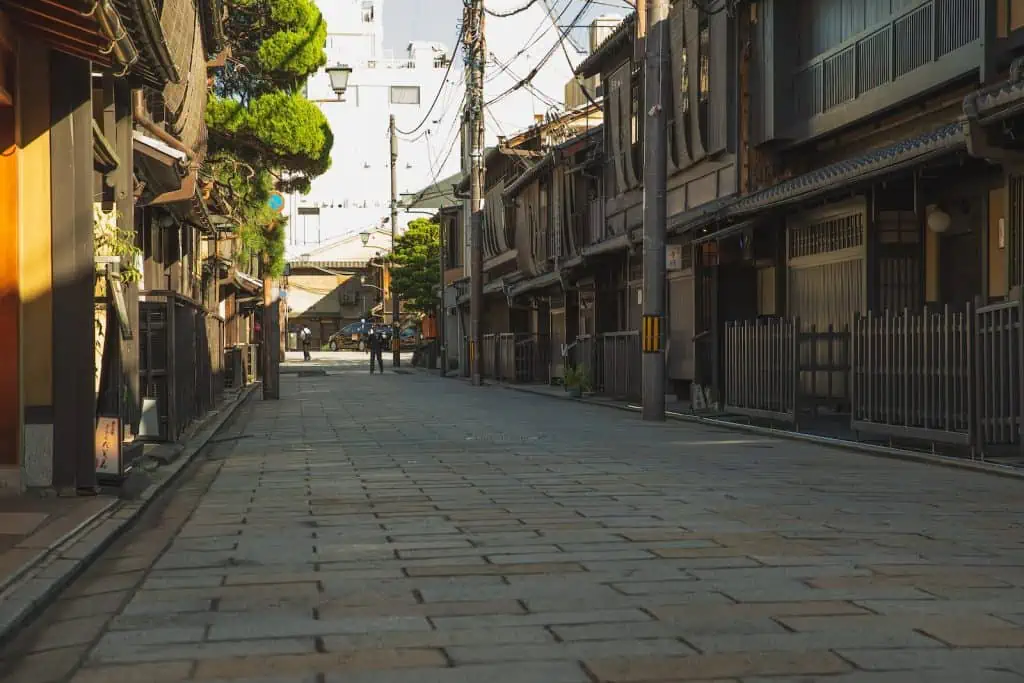 Empty paved street in historic district of Kyoto with aged residential houses on sunny day