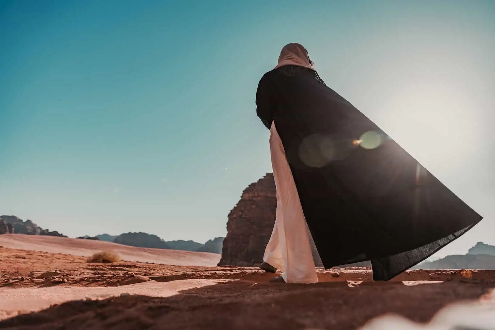 a woman in a black dress standing in the desert