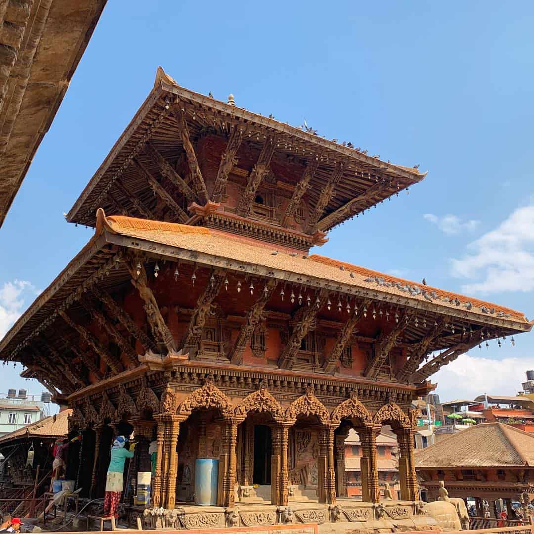 Two people cleaning the post of a temple